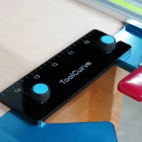 Black acrylic support tab with two blue thumb screws, mounted on blue TSO guide rail square with ruler markings