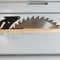 Wooden zero clearance insert with black metal blade holder and saw blade, displayed flat on white surface