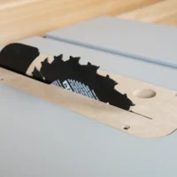 Wood zero clearance insert with black saw blade cutout, mounted on light blue FLEX table saw surface