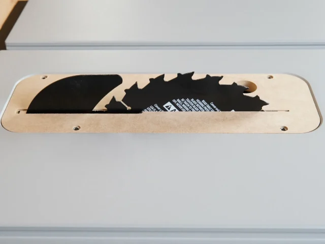 Zero clearance insert for FLEX 8-1/4" table saw, MDF base with cutouts for saw blade profiles, two mounting holes visible