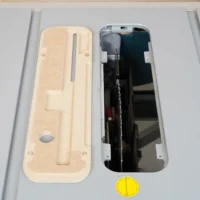 Cream MDF zero clearance insert next to black factory insert for Bosch 4100 table saw, showing cutout for blade and mounting holes