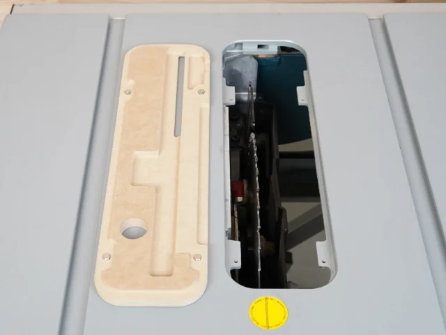 Cream MDF zero clearance insert next to black factory insert for Bosch 4100 table saw, showing cutout for blade and mounting holes