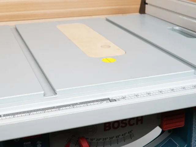 Cream MDF zero clearance insert seated in Bosch 4100 table saw, with yellow reference dot and wooden test piece visible on surface