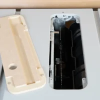 Cream-colored 3D-printed zero clearance insert next to white insert with black interior, both lying flat on white surface