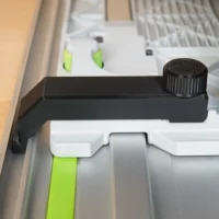 Black anti-tip guide attached to Festool TS 55 track saw rail, with adjustable knob on top end