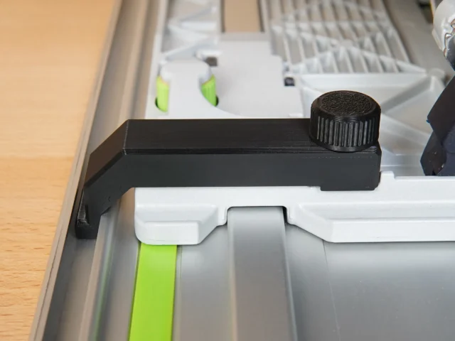 Black anti-tip guide attached to Festool TS 55 track saw rail, with adjustable knob on top end