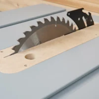 Bosch 4100 table saw zero clearance insert installed on saw table, showing wood base with circular blade opening and black metal blade guard overhead