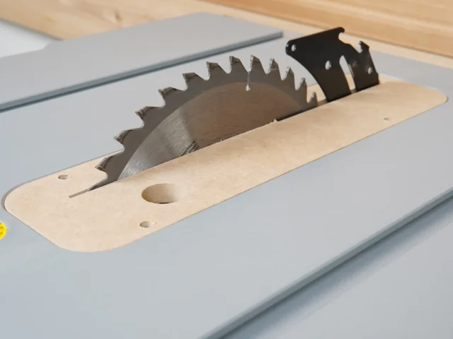 Bosch 4100 table saw zero clearance insert installed on saw table, showing wood base with circular blade opening and black metal blade guard overhead