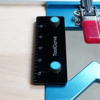 Black ToolCurve TSO guide rail square with blue adjustment knobs mounted on blue track saw rail, red anti-tip support tab attached above