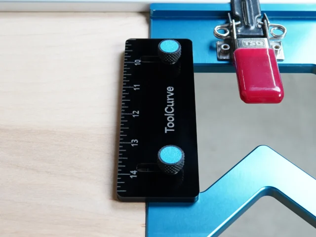 Black ToolCurve TSO guide rail square with blue adjustment knobs mounted on blue track saw rail, red anti-tip support tab attached above