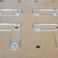 Four clear acrylic fence stops with threaded aluminum bench dogs, arranged on a workbench with 20mm holes