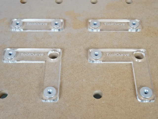 Four clear acrylic fence stops with threaded aluminum bench dogs, arranged on a workbench with 20mm holes