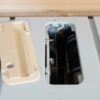 Zero clearance MDF insert for FLEX 8-1/4 inch table saw, shown removed from the saw with internal cavity and circular opening visible on left, dust collection chamber on right