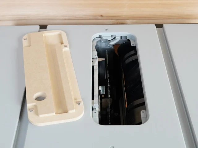 Zero clearance MDF insert for FLEX 8-1/4 inch table saw, shown removed from the saw with internal cavity and circular opening visible on left, dust collection chamber on right