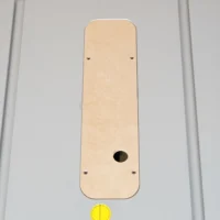 Cream-colored MDF zero clearance insert for Bosch 4100 table saw, rectangular with rounded corners, oval blade opening near bottom, and four adjustment screw holes