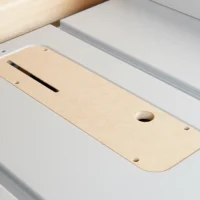 Light wood zero-clearance insert with curved edges and a long slot down the center, positioned in a white table saw throat