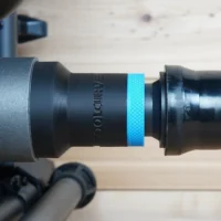 Black ToolCurve 1-1/4 inch hose adapter with blue textured band joining a vacuum hose to a SKIL table saw dust port