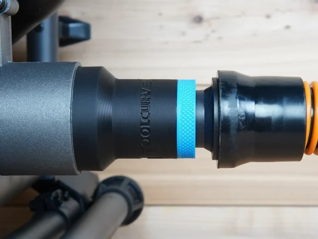 Black ToolCurve 1-1/4 inch hose adapter with blue textured band joining a vacuum hose to a SKIL table saw dust port