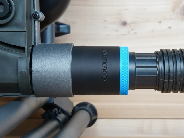 Black 1-7/8 inch ToolCurve hose adapter with blue ring joining a vacuum hose to a SKIL table saw dust port