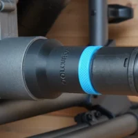 Black ToolCurve hose adapter with blue textured ring joining a SKIL table saw dust port to a vacuum hose