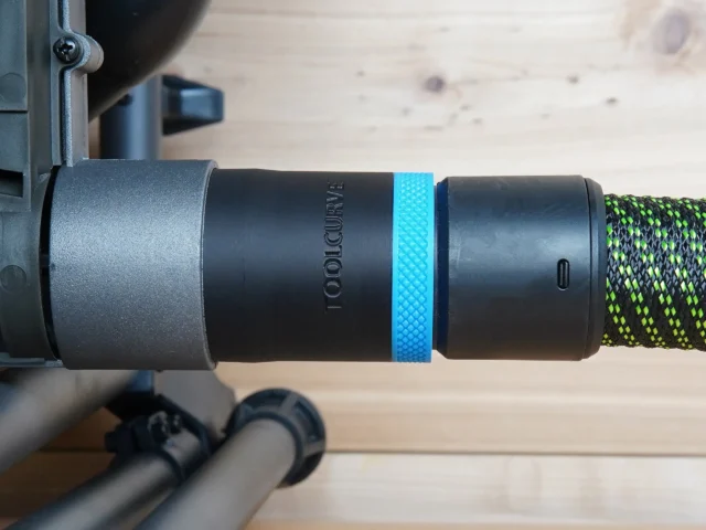 Black ToolCurve 36mm hose adapter with blue ring joining a dust extractor hose to a SKIL table saw port