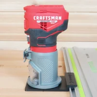 Craftsman 20v brushless router mounted on black guide rail adapter, positioned on Festool track saw rail on wooden workbench