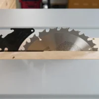 Zero clearance insert for Bosch GTS18 table saw, showing MDF base with black metal blade guard and exposed saw blade in aluminum track