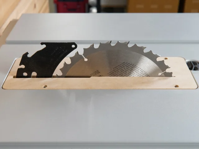 Zero clearance insert for Bosch GTS18 table saw, showing MDF base with black metal blade guard and exposed saw blade in aluminum track