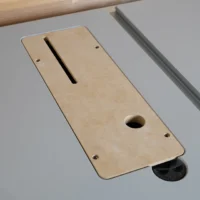 Light tan MDF zero clearance insert for Bosch GTS18 table saw, shown laid flat with a long slot and round hole visible, mounted on gray saw table