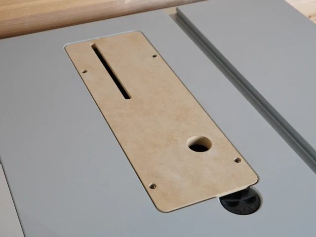 Light tan MDF zero clearance insert for Bosch GTS18 table saw, shown laid flat with a long slot and round hole visible, mounted on gray saw table
