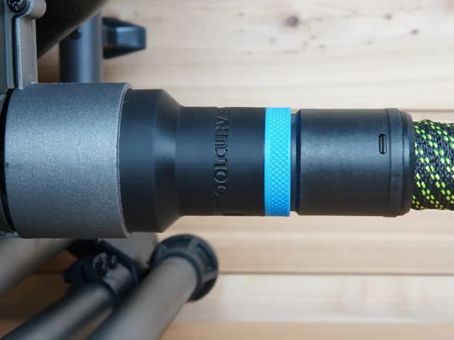 Black hose adapter attached to SKIL table saw dust port, with blue identification band and braided hose connected