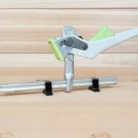 Set of stop blocks mounted on a metal quick clamp bar, with black stands supporting the rail and lime-green and light blue blocks limiting clamp travel