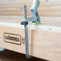 Black stop block mounted on metal shaft of Bessey quick clamp clamped to Sjöbergs MFT workbench