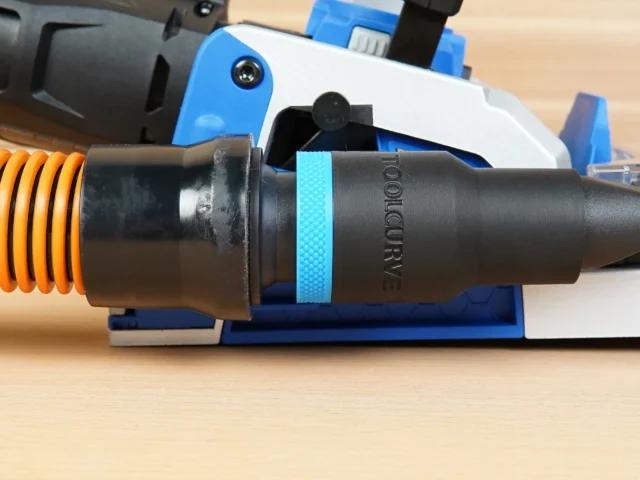 Black 1-1/4 inch hose adapter with blue grip ring joining an orange vacuum hose to a Kreg Rebel joiner port