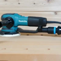 Black 1-1/4 inch hose adapter with blue band installed on a Makita random orbit sander, second adapter alongside