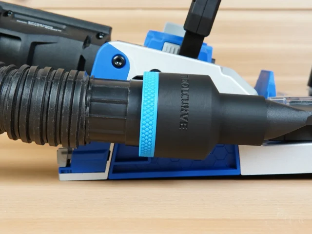 Black 1-7/8 inch hose adapter with blue grip ring joining a vacuum hose to a blue Kreg Rebel joiner port