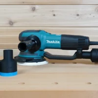 Black and blue ToolCurve 1-7/8 inch hose adapter shown twice beside a Makita random orbit sander, one joined to a vacuum hose