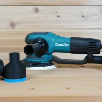 Black ToolCurve 2-1/2 inch hose adapter with blue trim beside a Makita random orbit sander