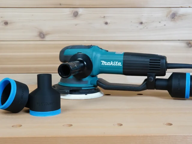 Black ToolCurve 2-1/2 inch hose adapter with blue trim beside a Makita random orbit sander
