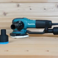Black ToolCurve 36mm hose adapter with blue ring installed on a Makita random orbit sander, spare shown beside