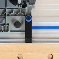 Black PETG anti-tip guide mounted on Kreg ACS track saw positioned over aluminum rail, blue connector visible at top