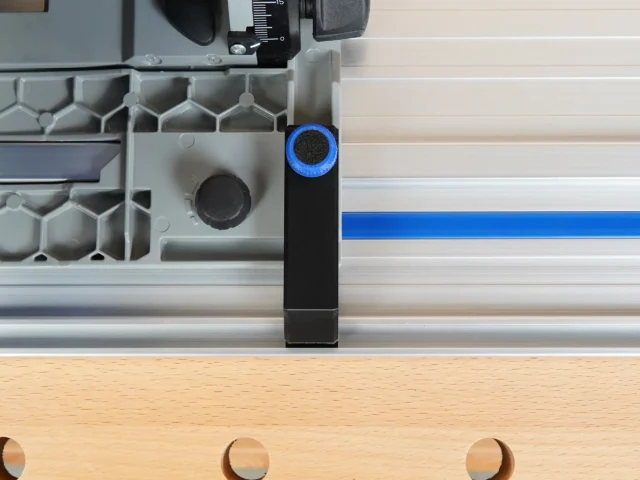 Black PETG anti-tip guide mounted on Kreg ACS track saw positioned over aluminum rail, blue connector visible at top