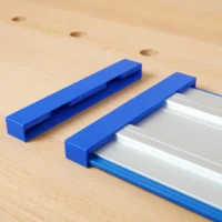 Two blue PETG protective caps, one detached and one fitted over the end of a silver Kreg Accu-Cut guide rail
