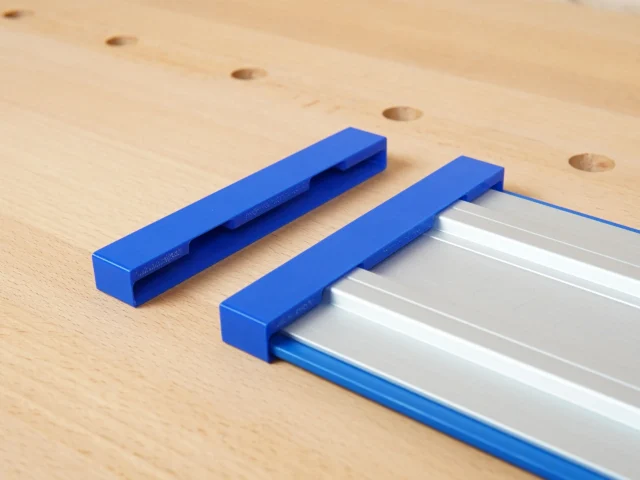 Two blue PETG protective caps, one detached and one fitted over the end of a silver Kreg Accu-Cut guide rail