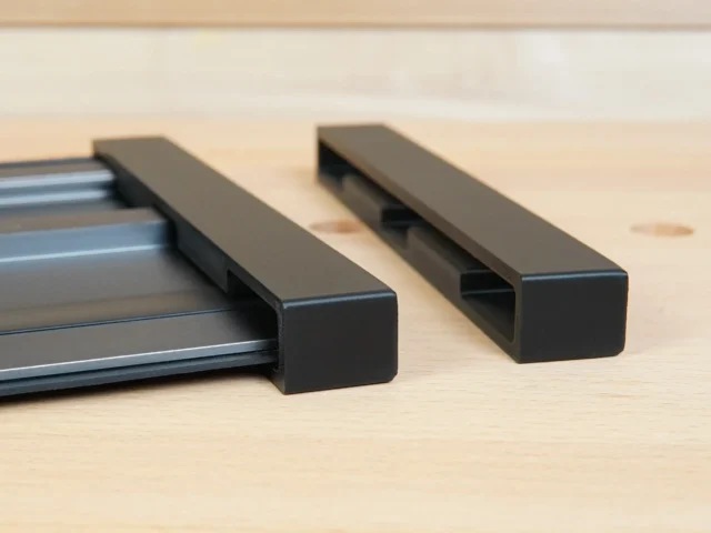 Two black protective caps for Ridgid track saw rails, one installed on an aluminum rail and one shown separately