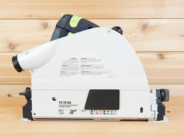 White arbor dust cover installed on Festool TS 75 track saw, showing snap-on design and safety warnings on blade guard