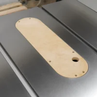 Light wood zero clearance insert with rounded edges and mounting holes, seated in a SawStop table saw slot