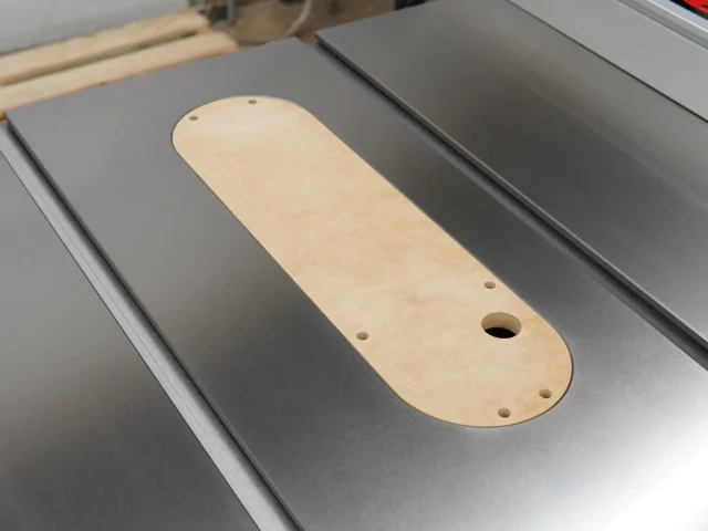 Light wood zero clearance insert with rounded edges and mounting holes, seated in a SawStop table saw slot