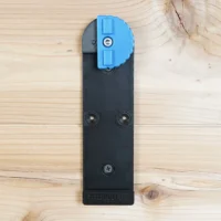 Black plastic wall mount with blue lever clamp for Kreg Accu-Cut track saw rail, shown flat with three screw holes visible