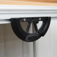 Black sander holder mounted to Festool MFT/3 table's T-track rail, showing open cradle design with mounting screws visible